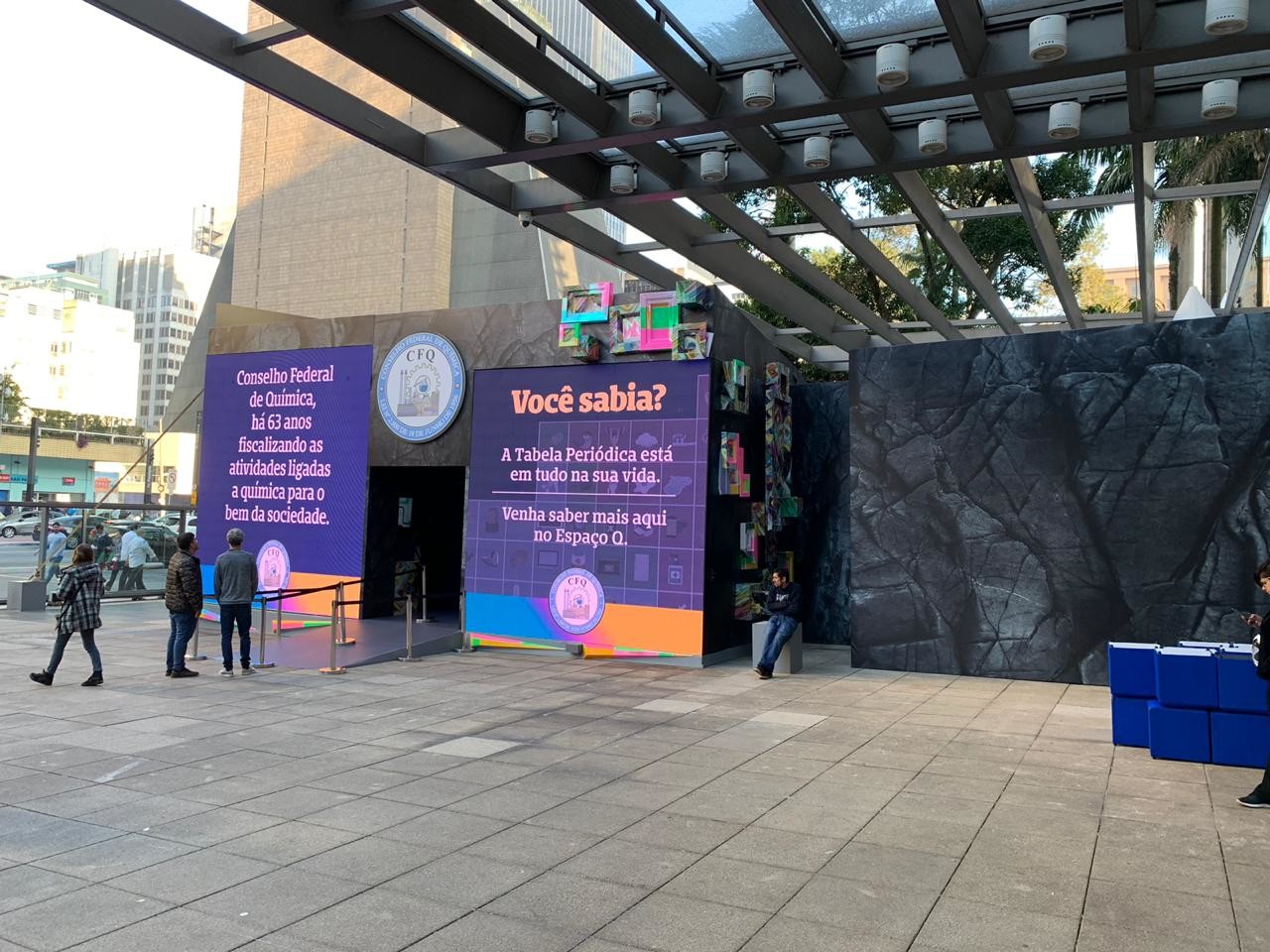 Entrance to the Espaço Q pavilion under the shopping-centre canopy, its dark bismuth-textured walls facing the street