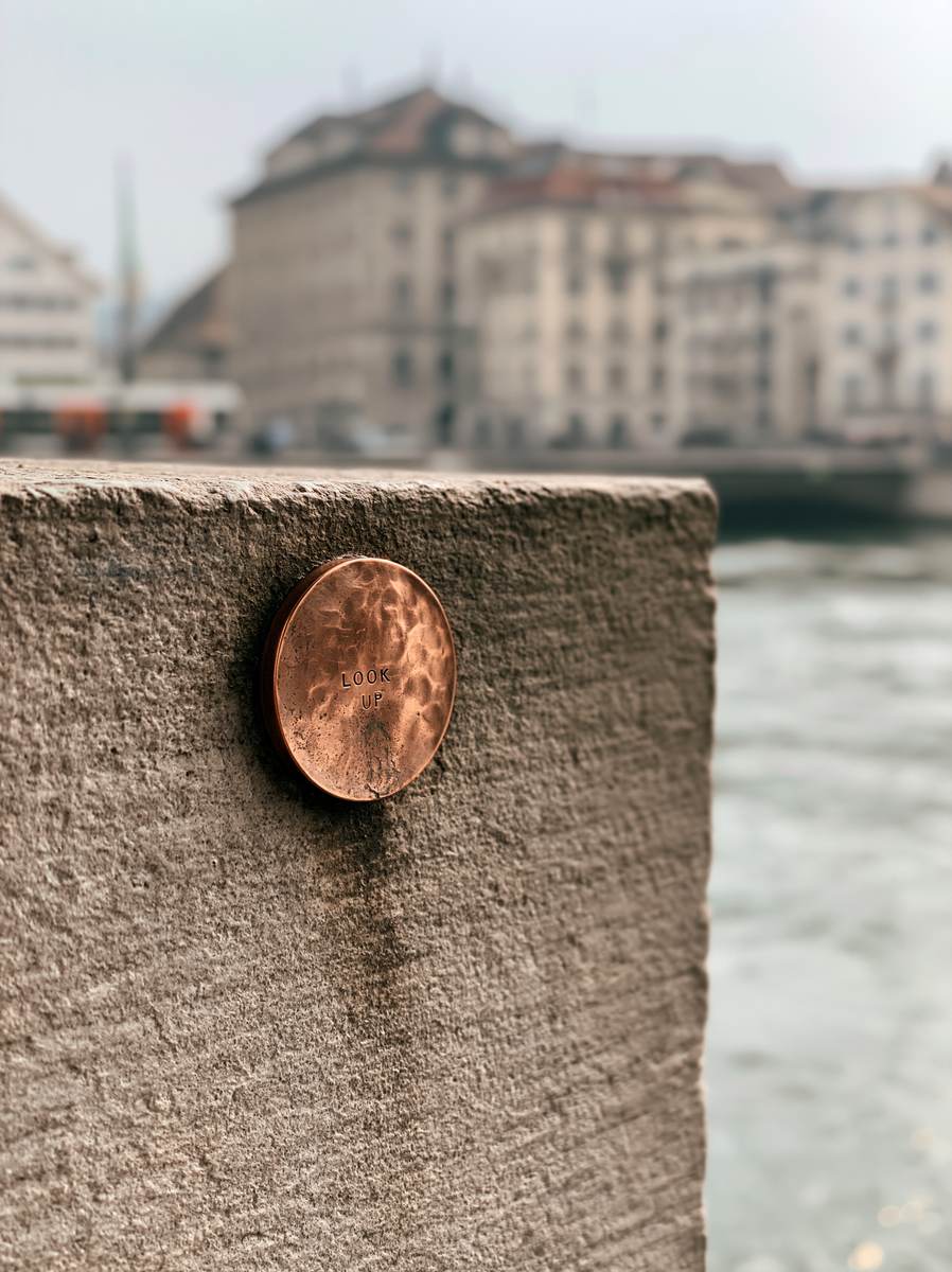 LOOK UP — hammered copper disc set into a riverside path, Zürich
