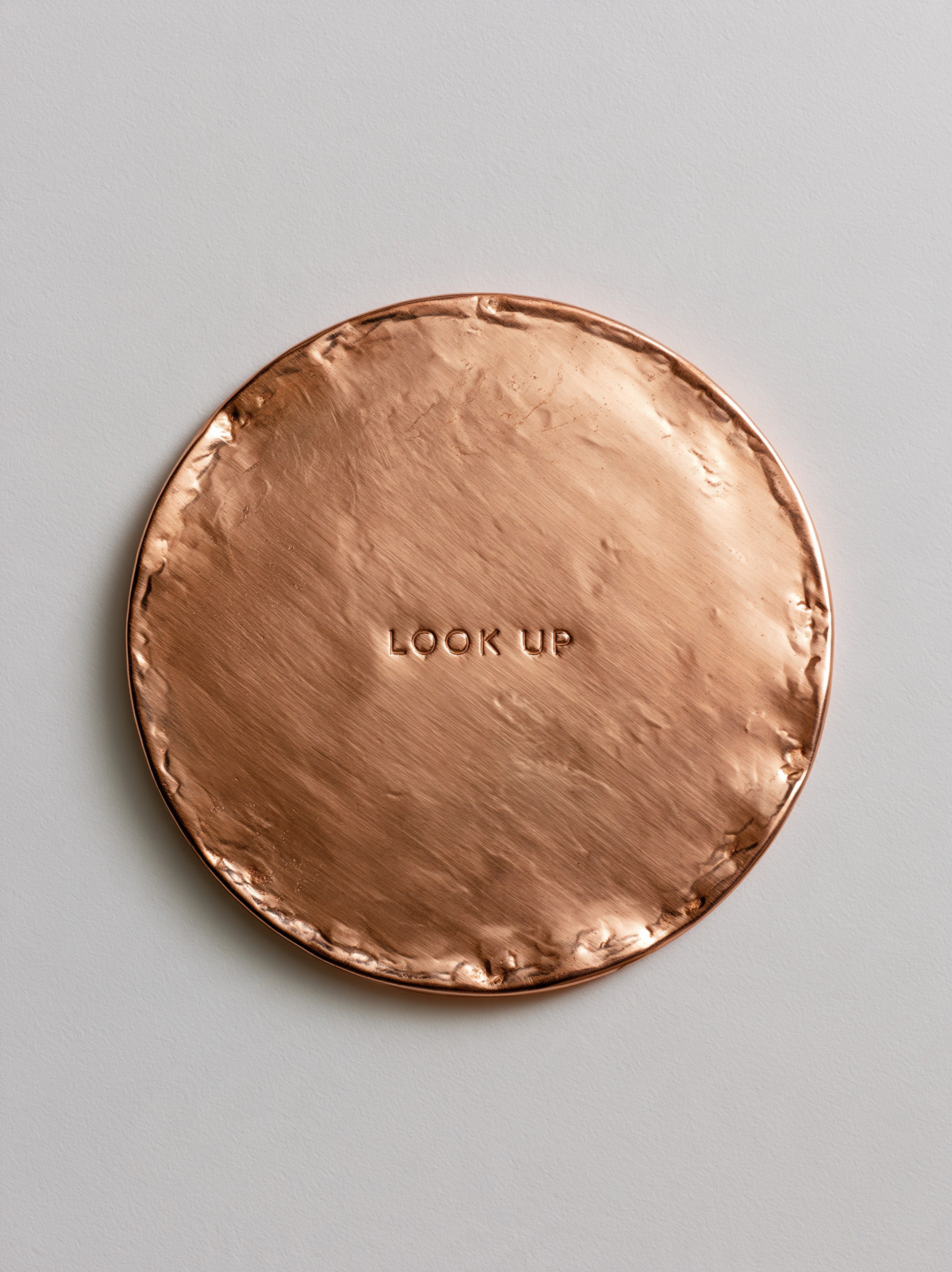 The LOOK UP disc, hammered copper, in place on a stone wall