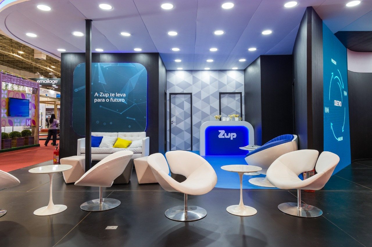 ZUP · 2019 · CIAB — A lounge of white moulded chairs and low tables on a blue exhibition floor.