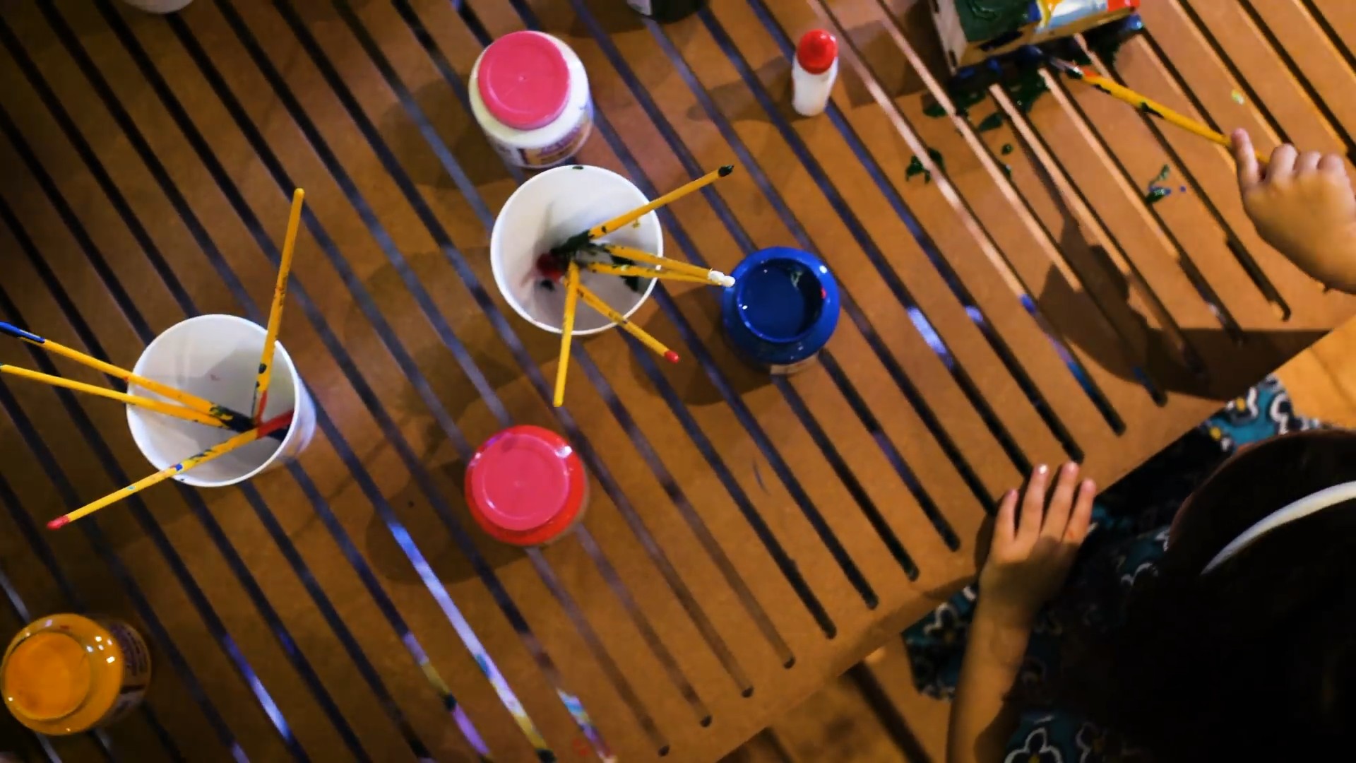 Paint pots and brushes on a slatted workbench, from above