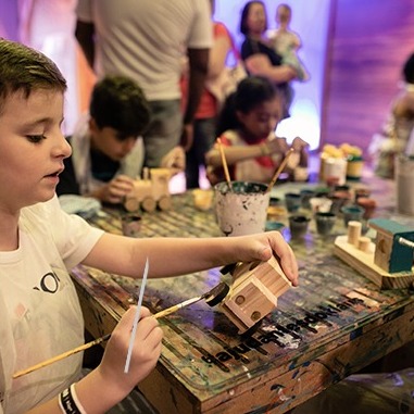 Painting a wooden toy at the workbench