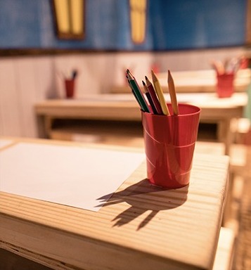 School desk with a cup of coloured pencils