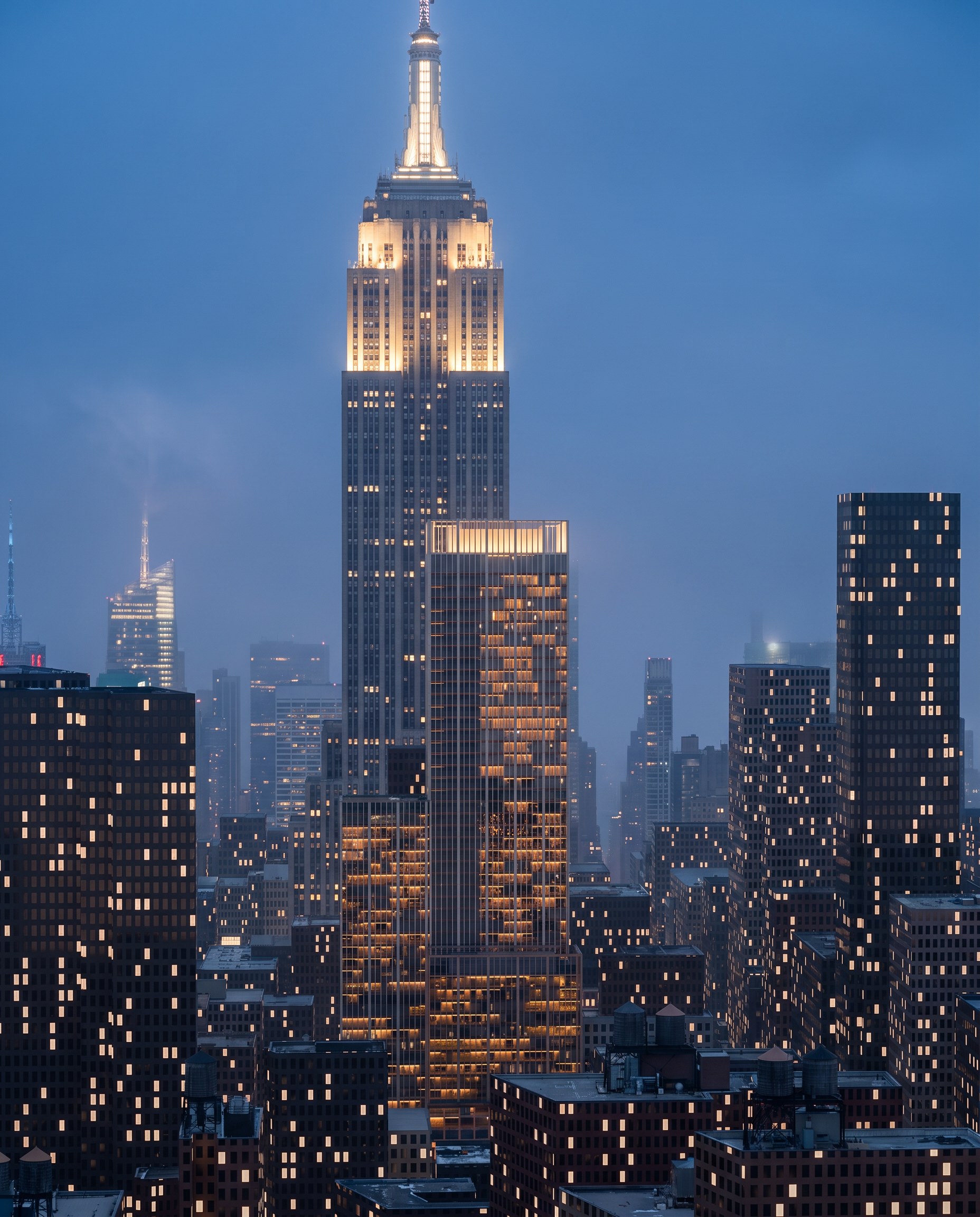 The north tower's crown at blue hour from the south, with the Empire State Building directly behind it