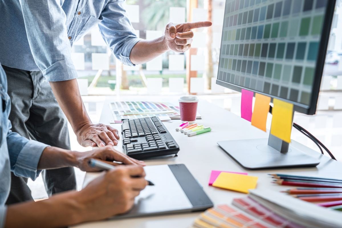 Two designers reviewing colour palettes and a website layout at a monitor