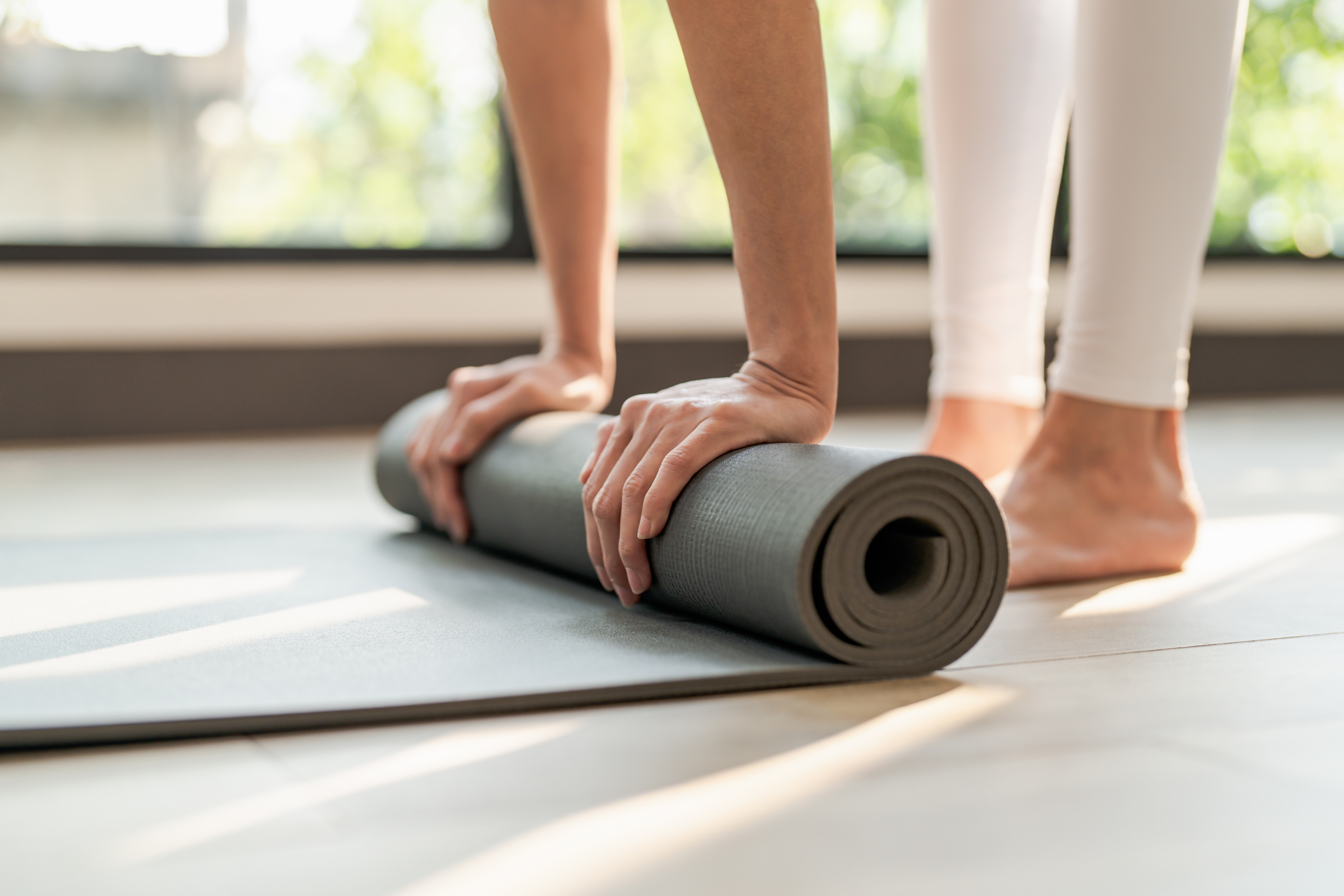 Woman rolling up yoga mat stock image