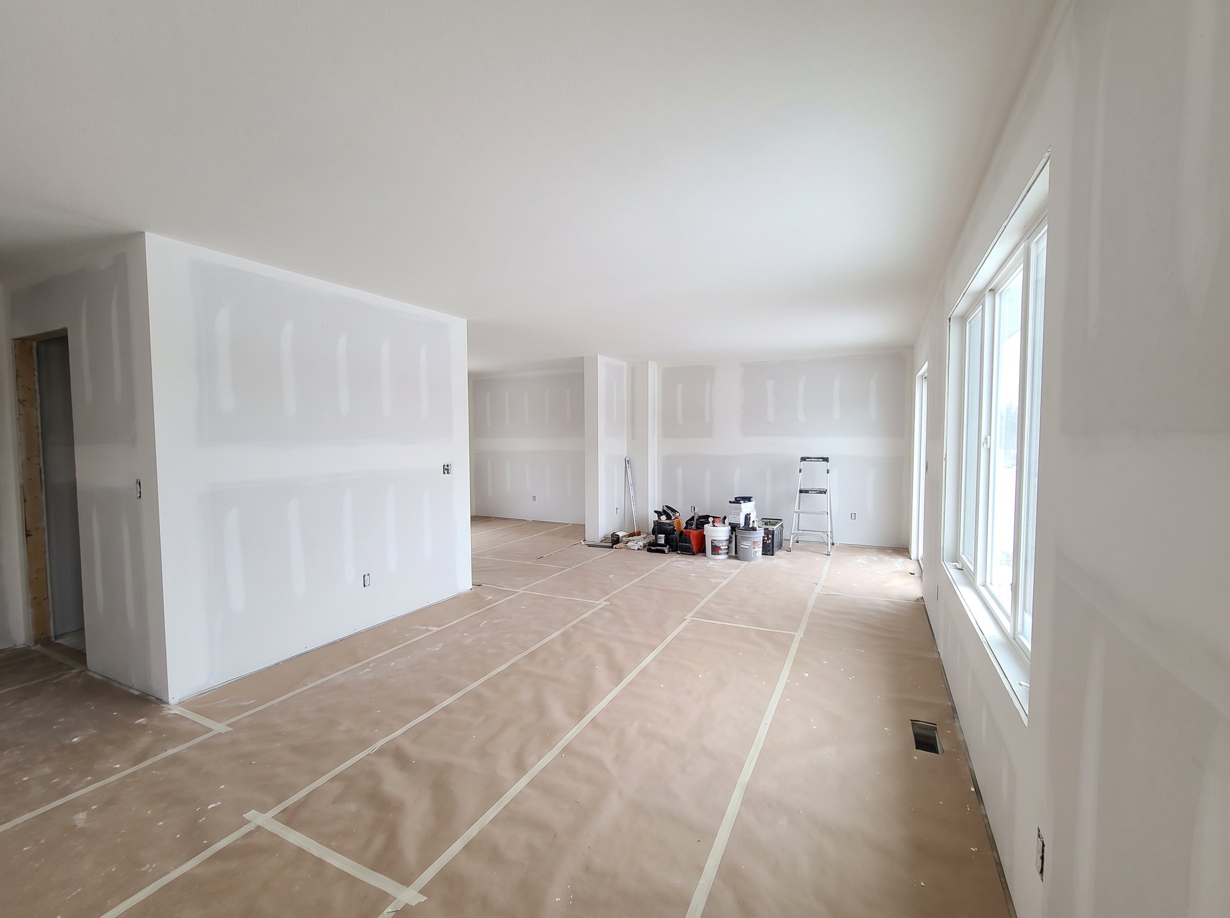 Room with newly hung drywall, seams taped and floors covered
