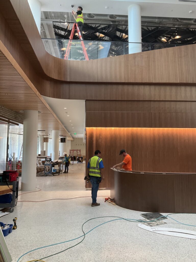 Workers in safety vests inside modern building under construction with wooden panel walls and tools around.
