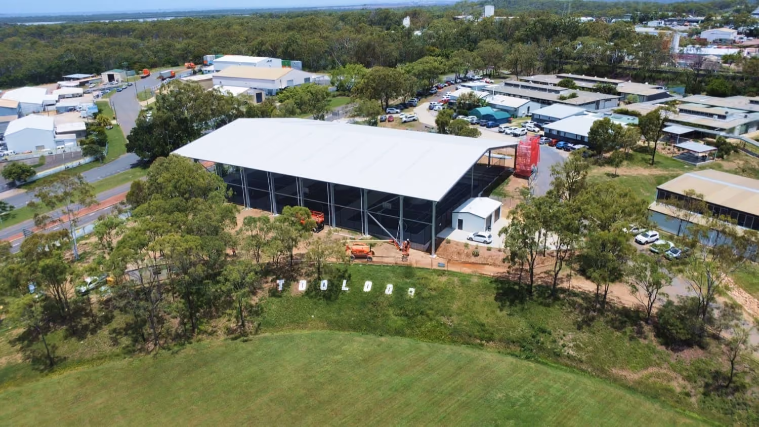 Aerial view of a large industrial shed surrounded by trees in a business park
