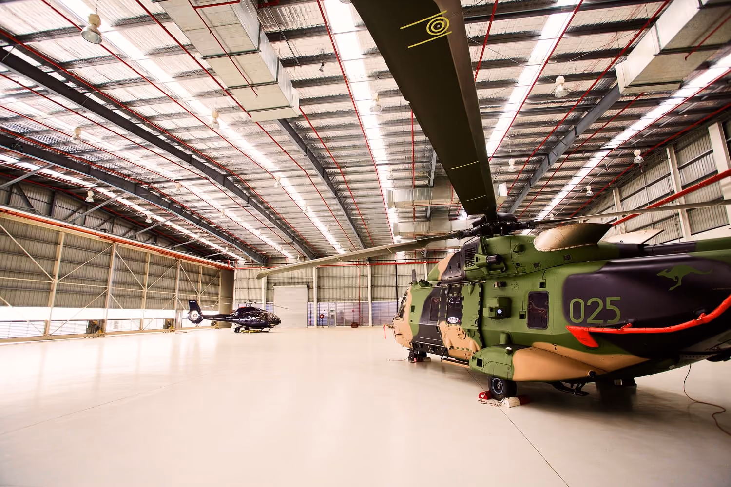 Military helicopter parked inside a large aircraft hangar