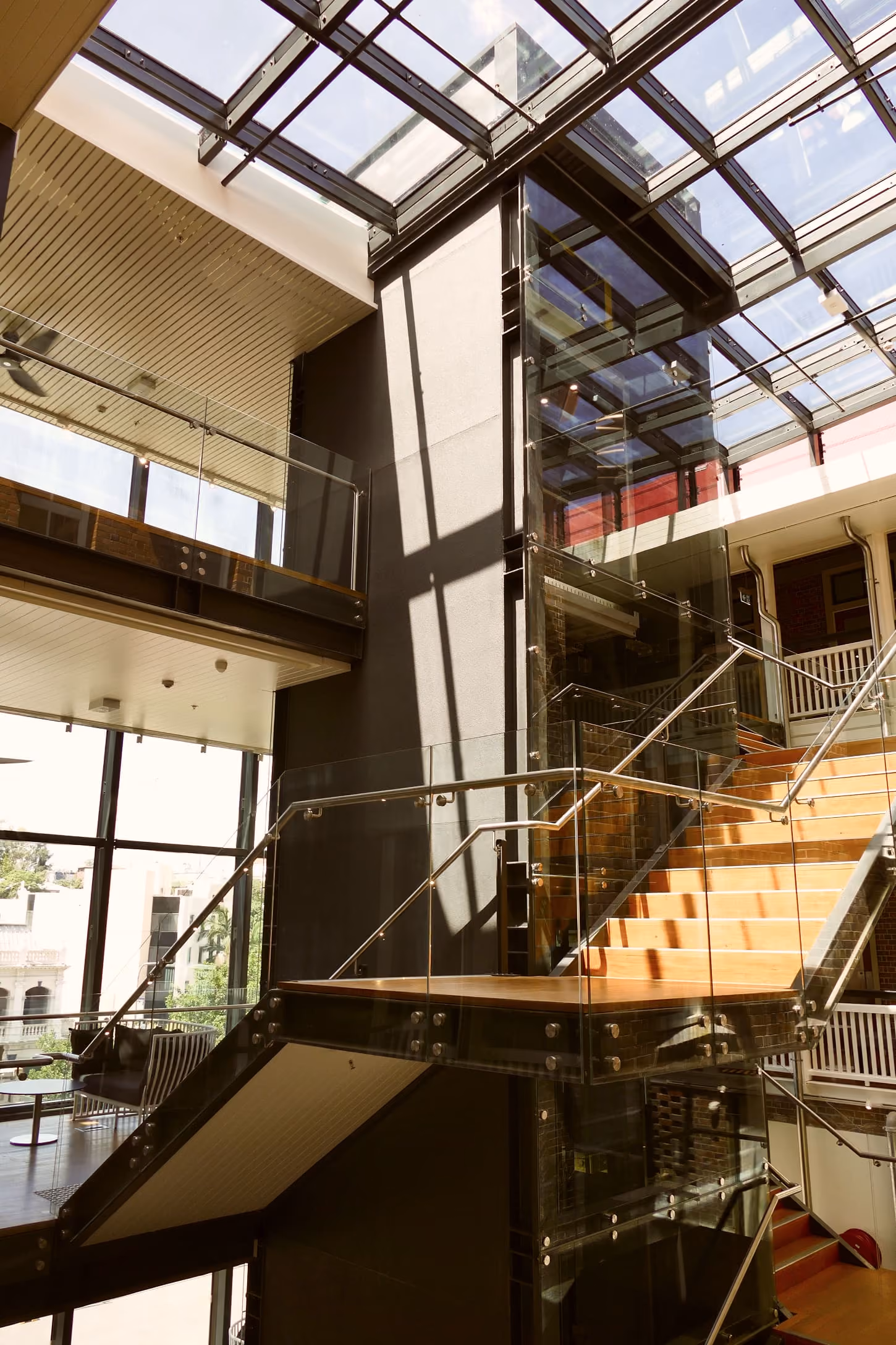 Multi-level atrium with timber stairs and a glass roof inside a commercial building