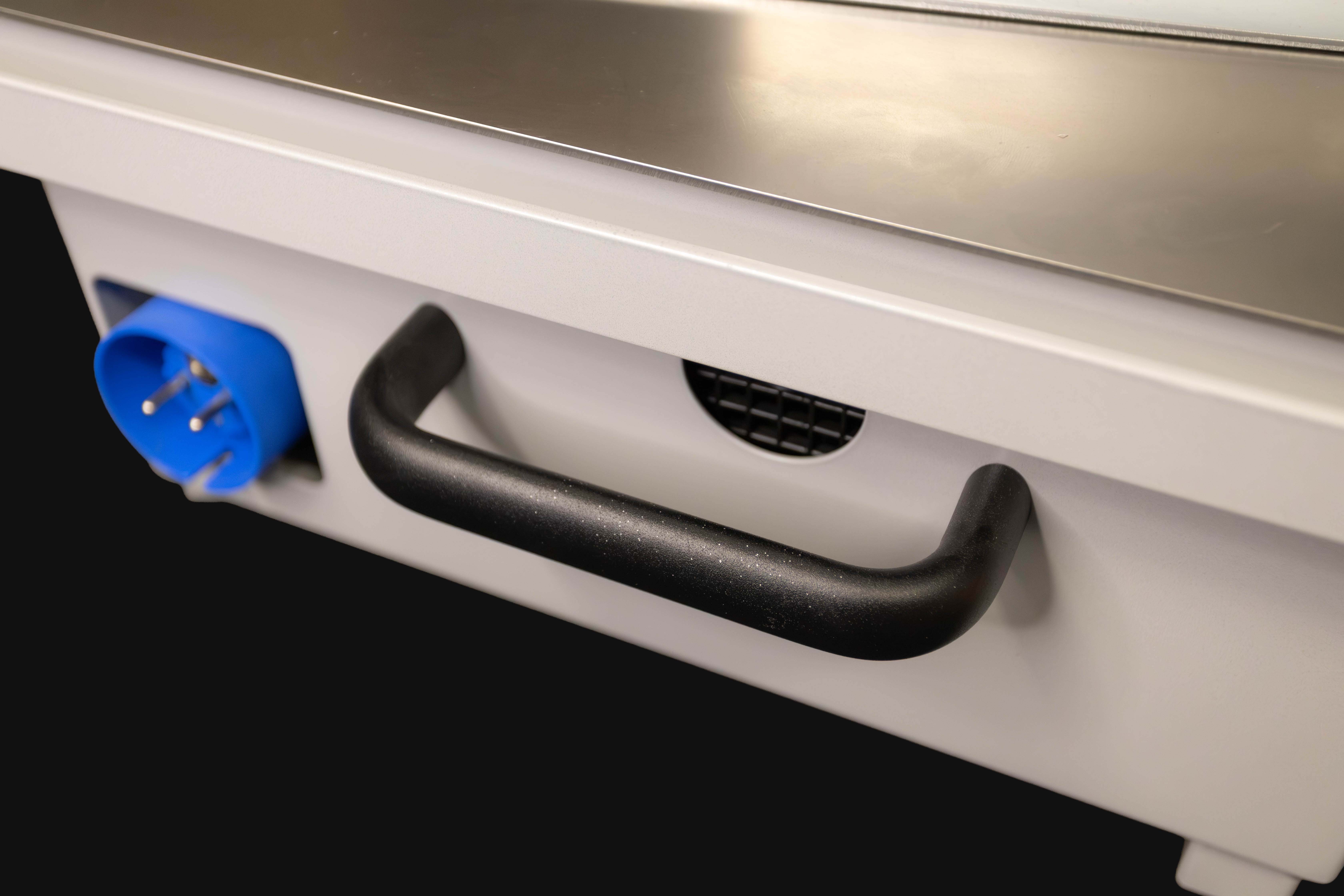 Vorderer Teil eines weißen elektronischen Geräts mit schwarzem Griff, blauem Steckeranschluss und Lüftungsgitter.