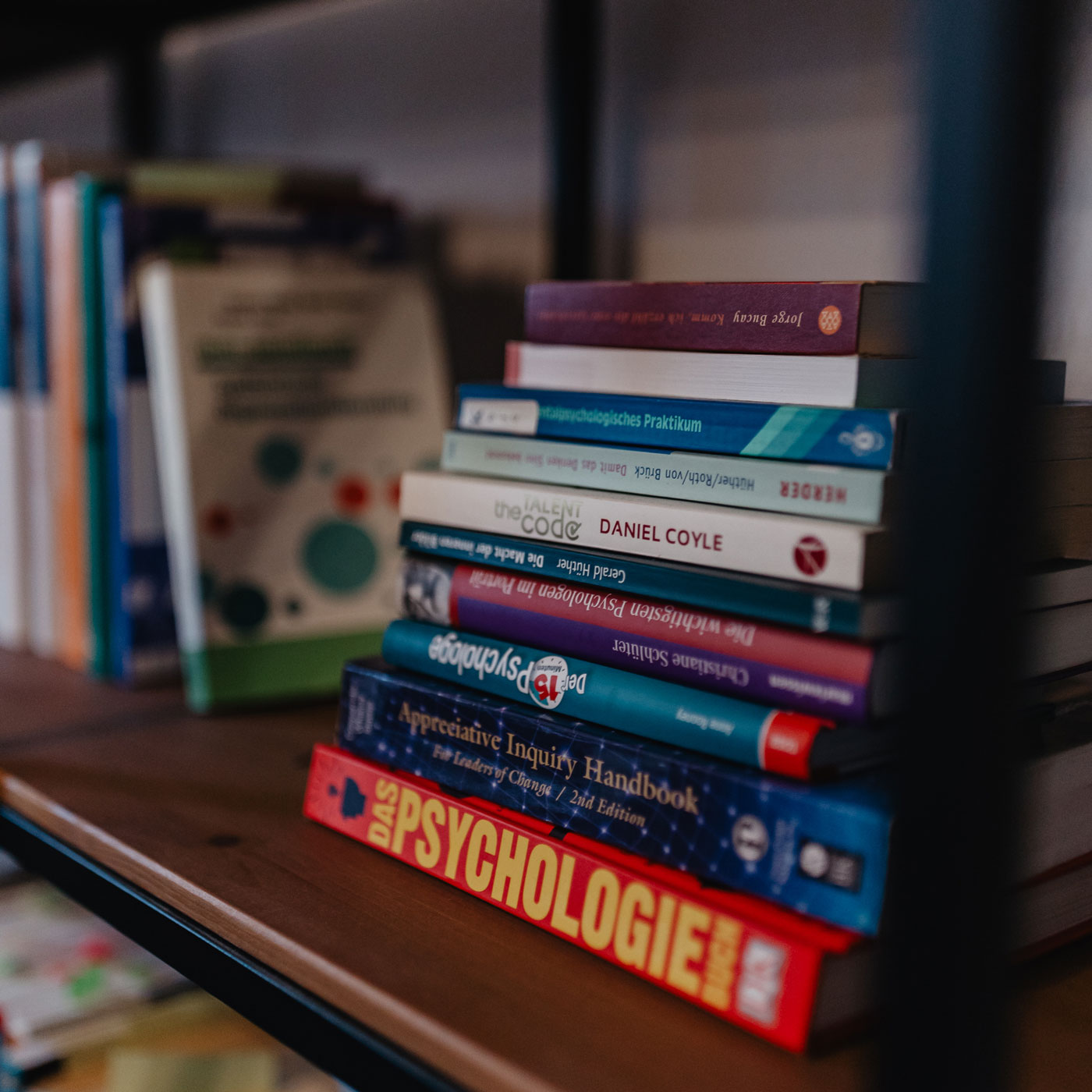 Stapel Fachbücher zu Psychologie, Coaching und Appreciative Inquiry in einem Regal