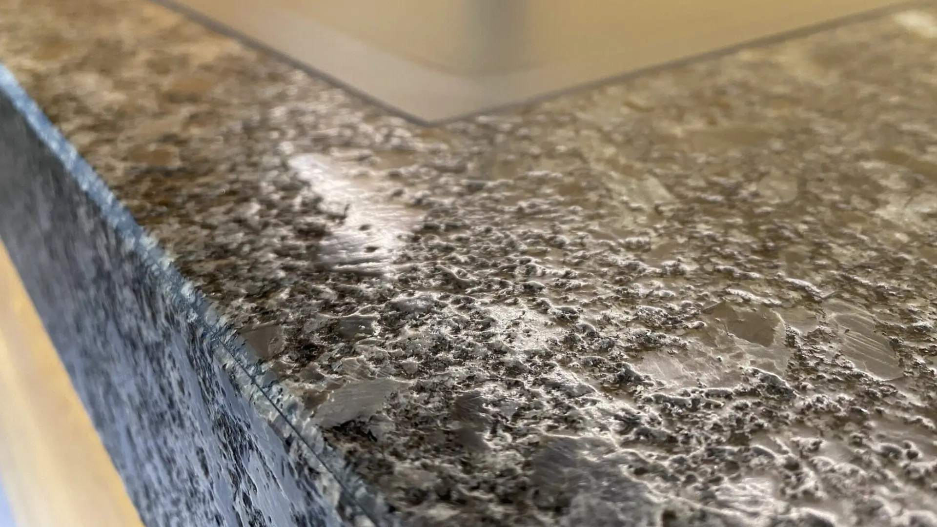 Nahaufnahme einer polierten dunkelgrauen Stein- oder Metalloberfläche mit strukturierter Textur.
