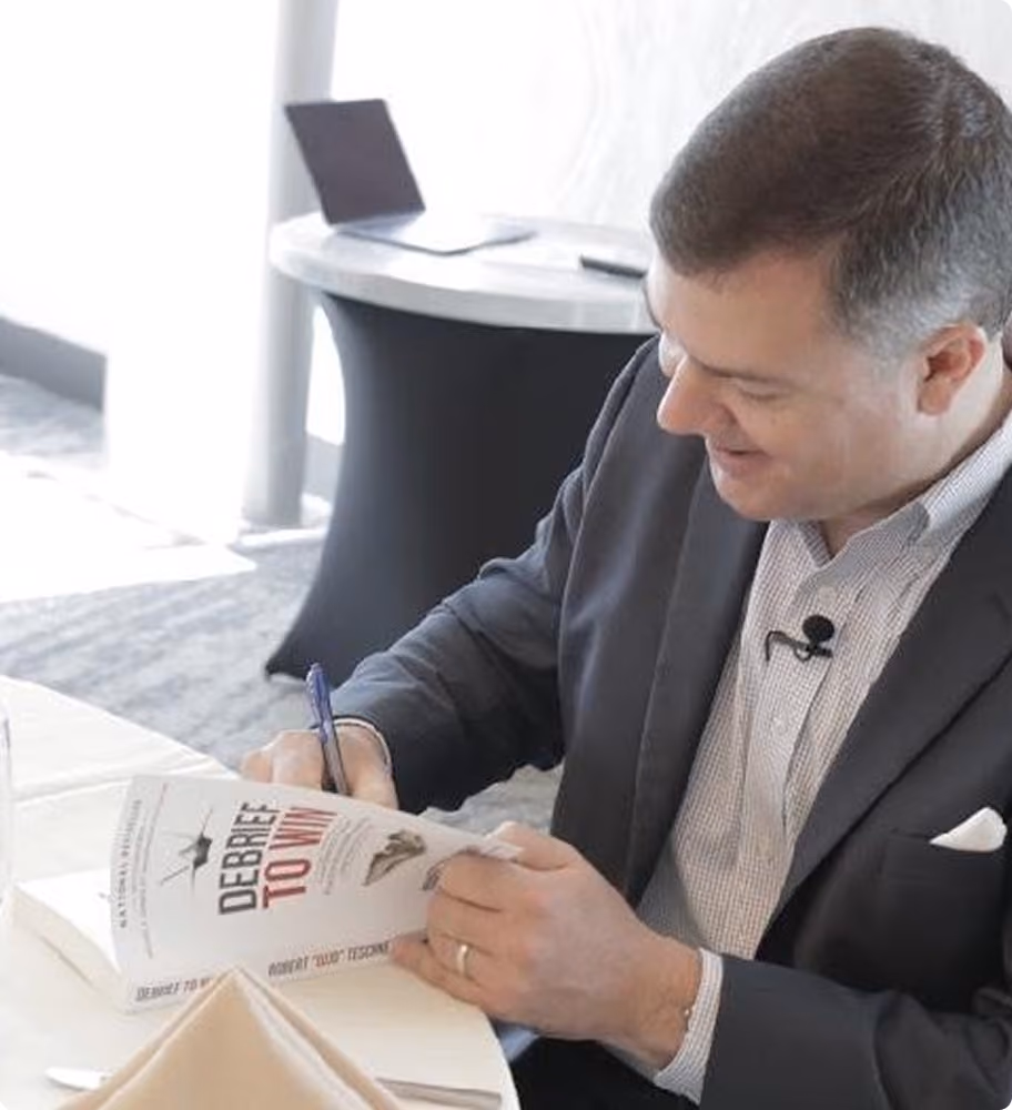 Robert "Cujo" Teschner signing a copy of Debrief to Win for a teamwork training participant