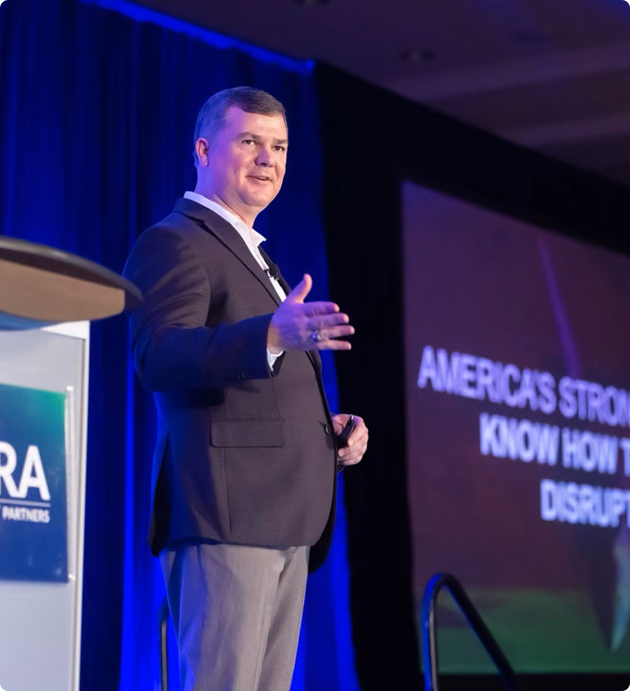 Robert "Cujo" Teschner speaking on stage at a leadership training conference