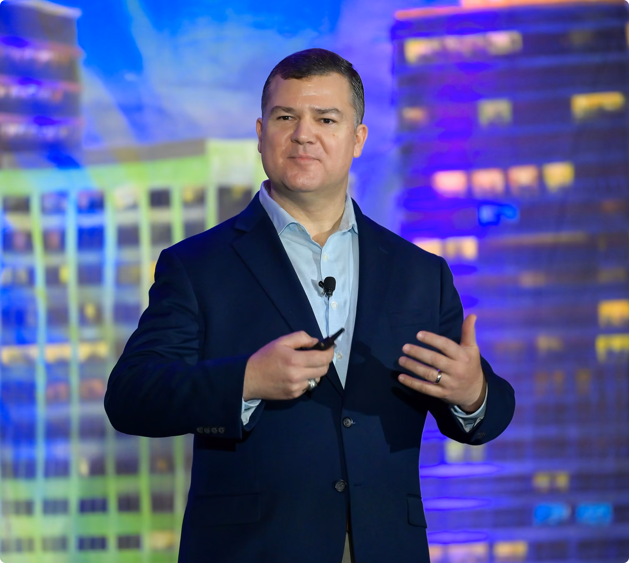 Robert "Cujo" Teschner delivering a leadership keynote with a city skyline projected behind him
