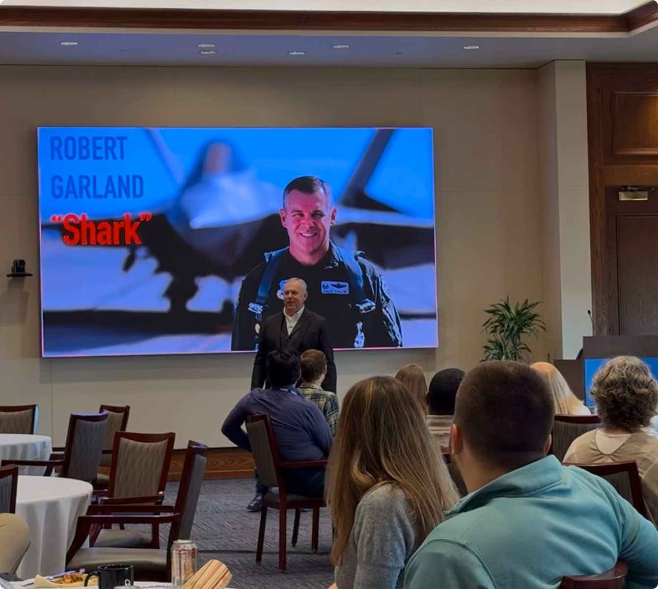 Robert "Shark" Garland leading a leadership workshop with his F-22 pilot photo on the screen