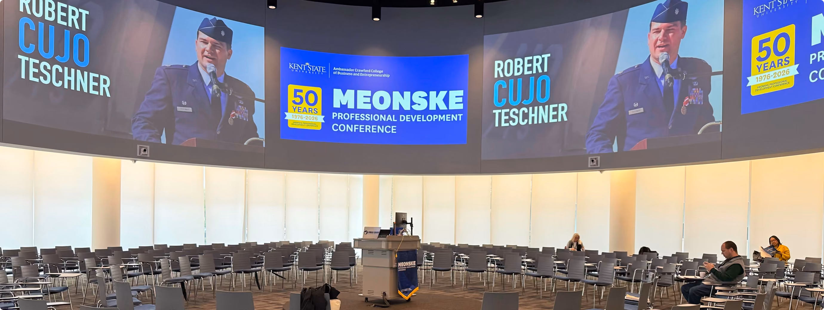Robert "Cujo" Teschner delivering a leadership keynote at the Meonske Professional Development Conference, shown on screens across the hall
