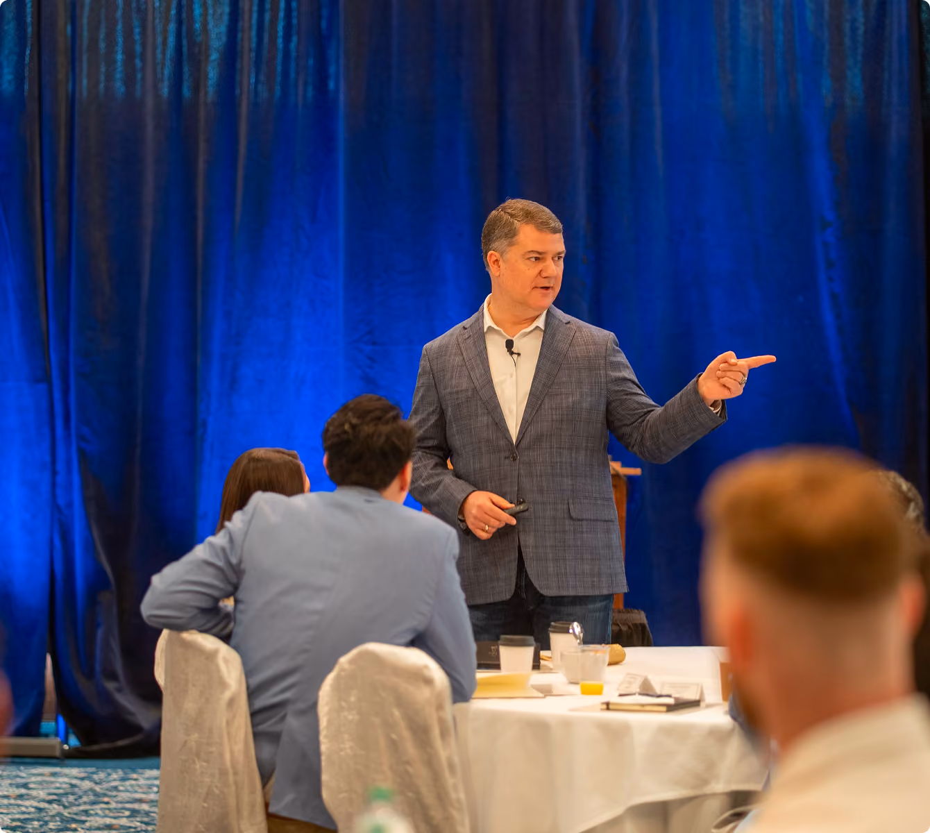 Robert "Cujo" Teschner leading a teamwork training discussion with participants at round tables
