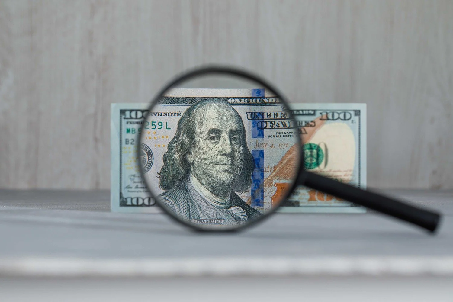 A magnifying glass held over a US hundred dollar banknote