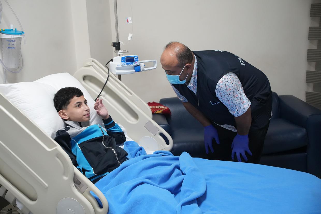 A FAJR clinician caring for a child in a hospital bed before medical evacuation.