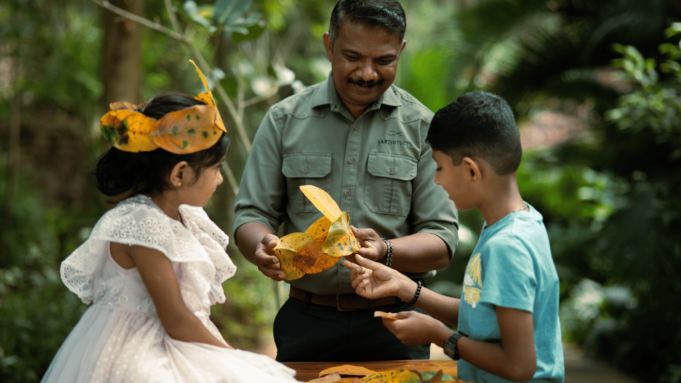 Staff showing two children a craft folded from dried leaves