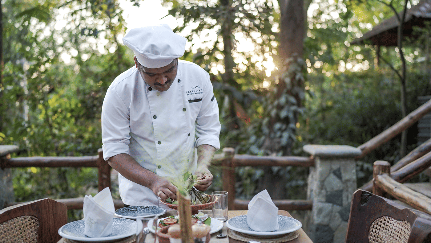 A chef plating dinner at an outdoor table on the deck