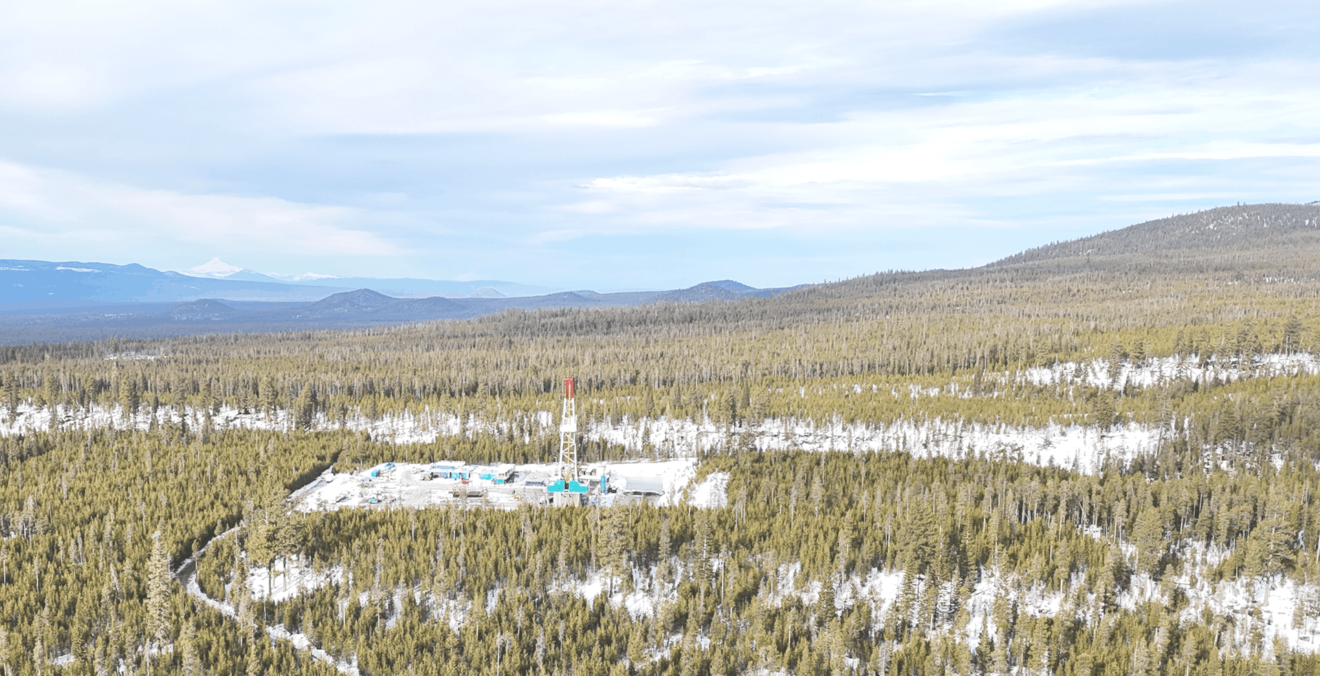 Aerial view of a geothermal well pad in a forested landscape