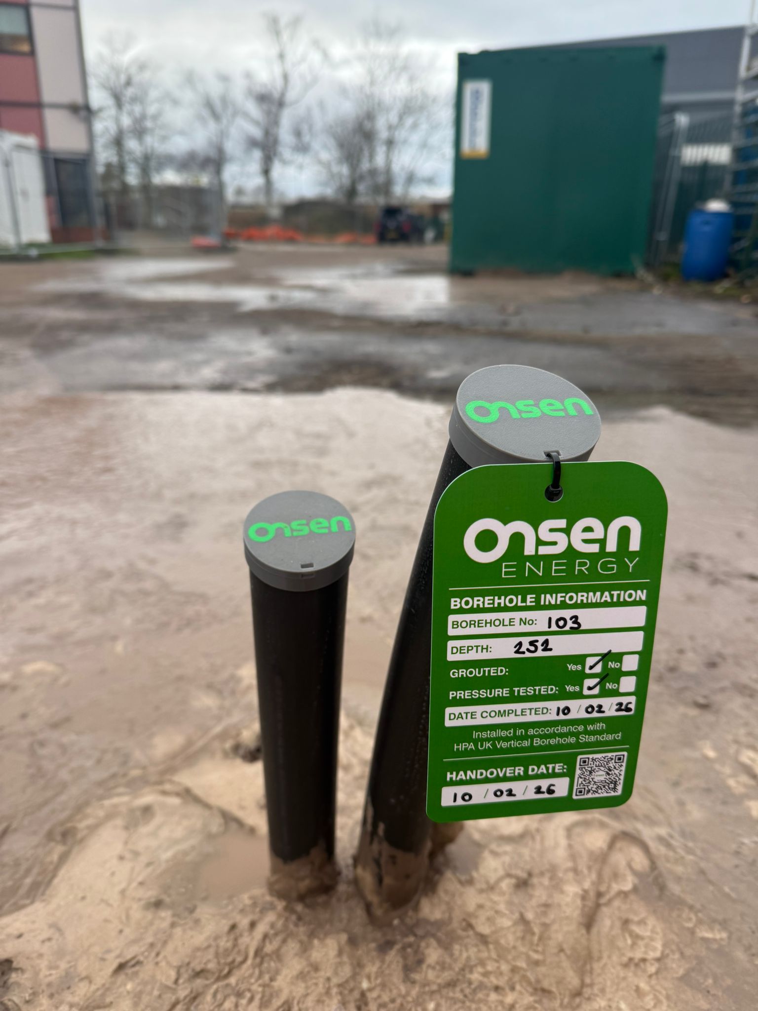 Completed Onsen Energy borehole pipes with a green information tag and QR code.
