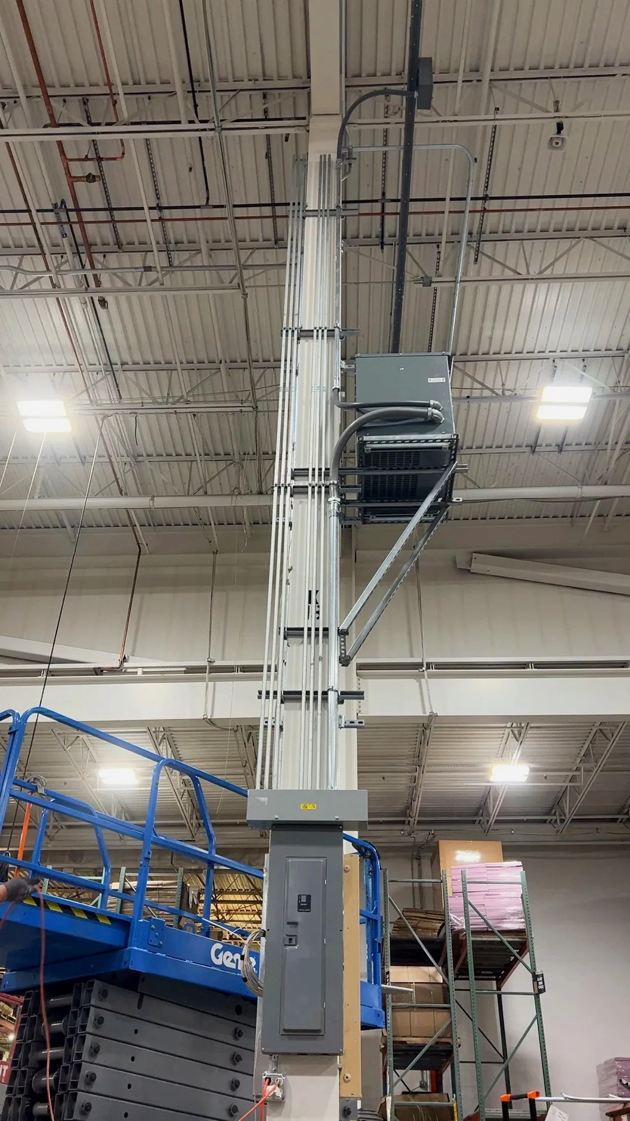 Overhead transformer and conduit mounted near the ceiling of an industrial building
