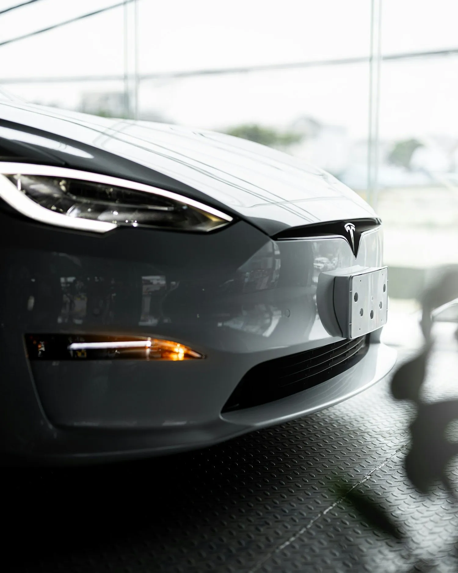 Front of a gray Tesla parked indoors in a showroom