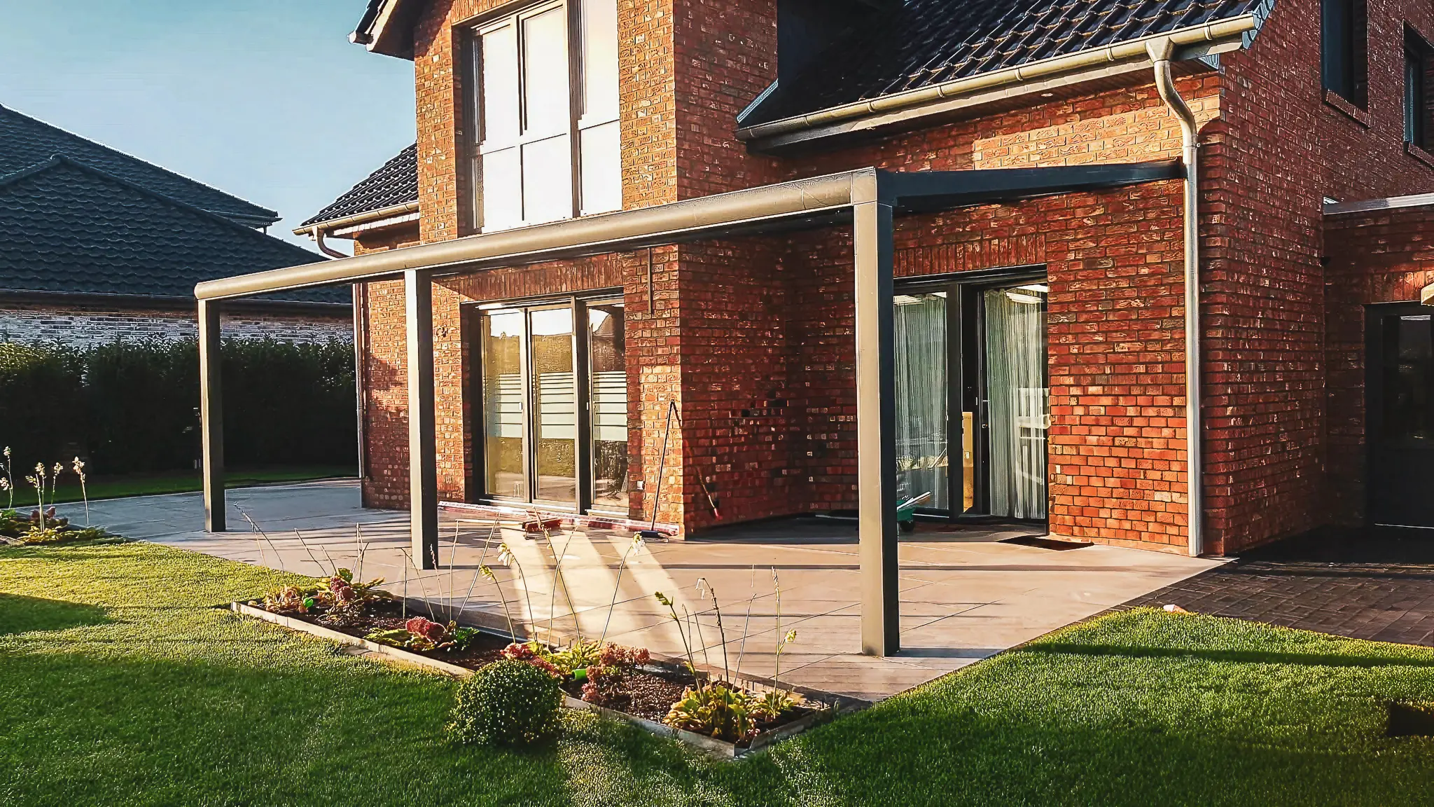 Ziegelhaus mit Terrasse, Pergola und gepflegtem Garten im Sonnenlicht