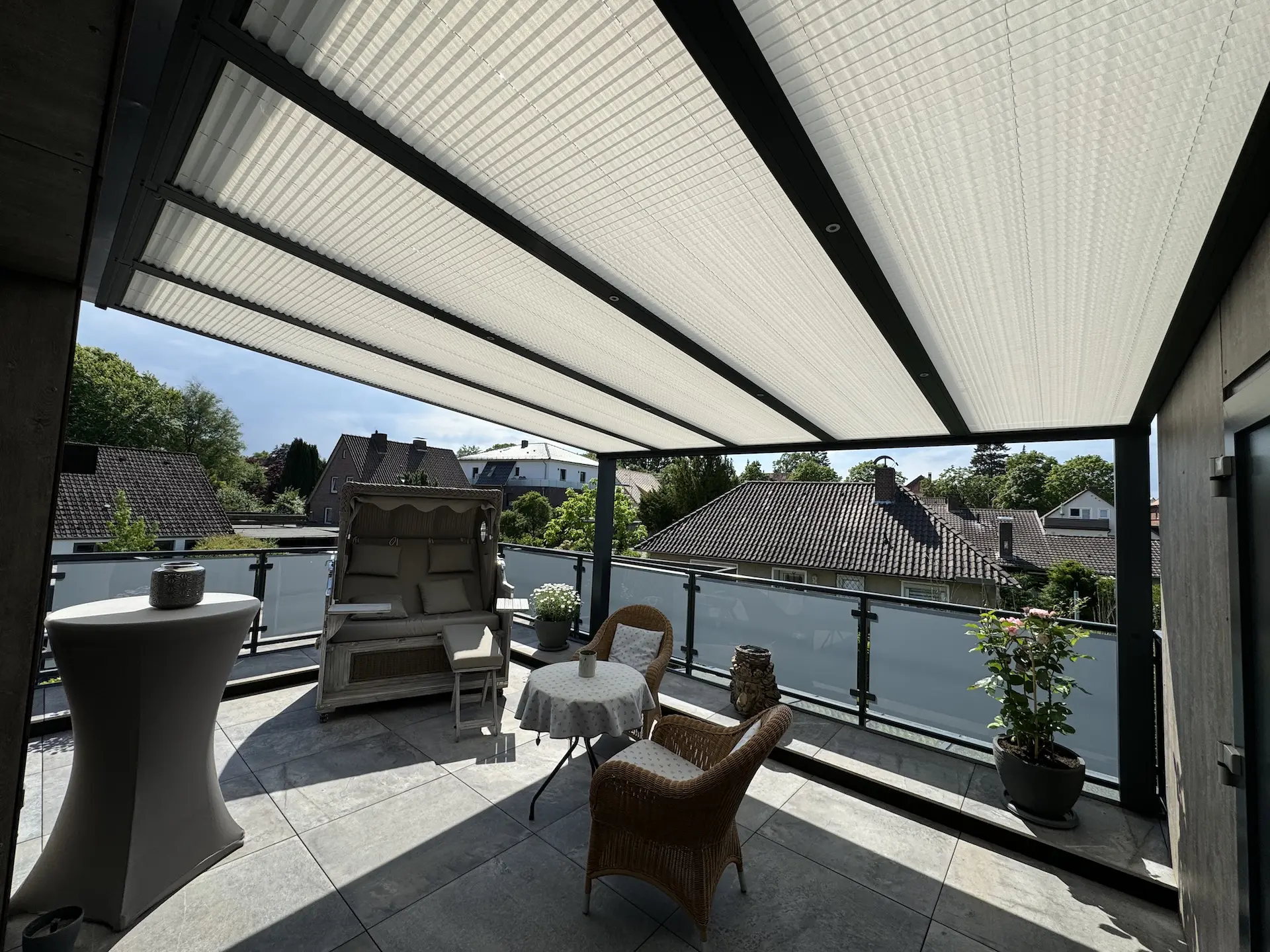 Sonnige Dachterrasse mit Überdachung, Möbeln und Blick auf Nachbarhäuser