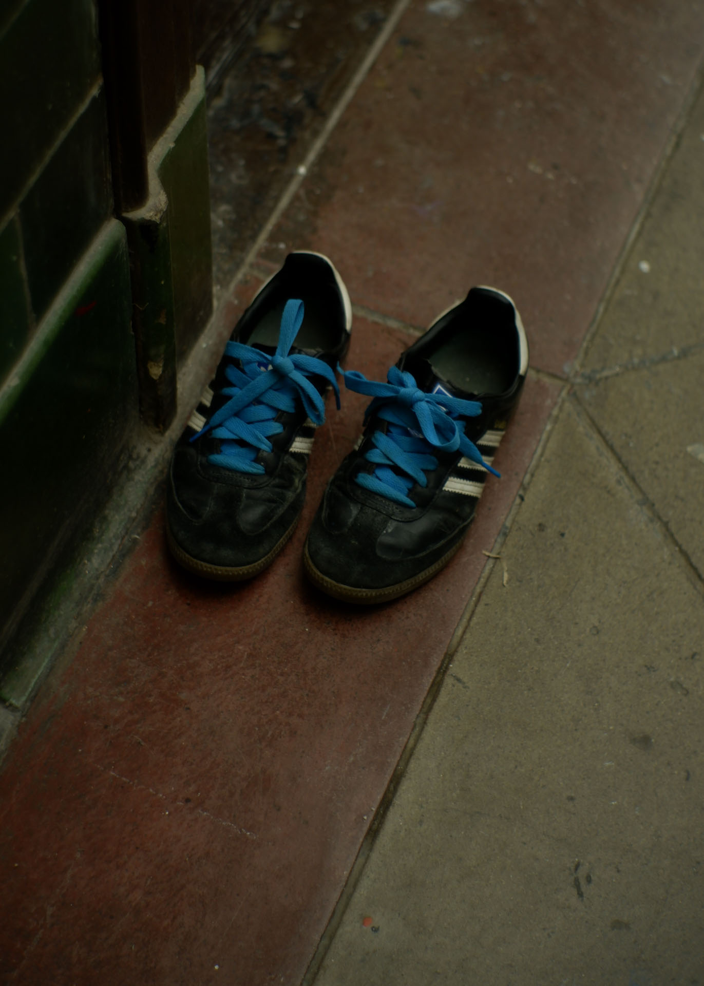 A pair of shoes with blue laces on the floor.