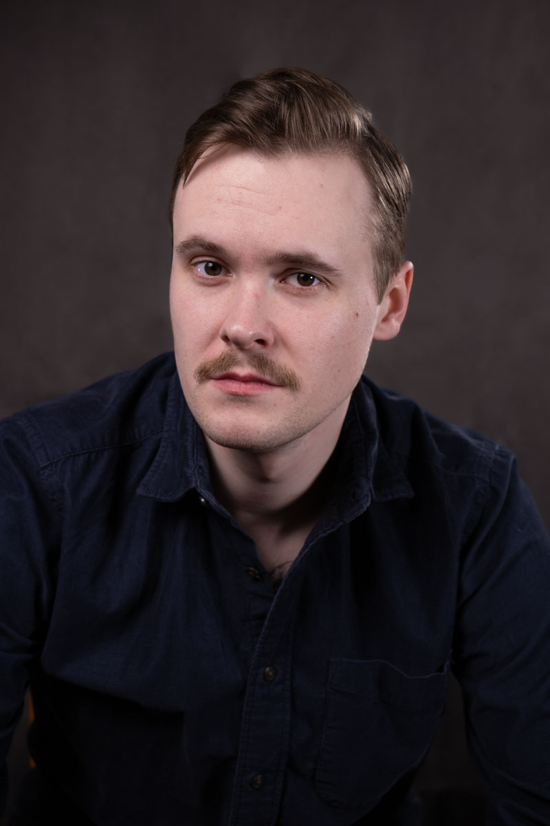 A portrait of a man against a gray background.