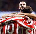 Two soccer players in red and white striped jerseys embracing in celebration, one facing forward and the other with back showing number 10.