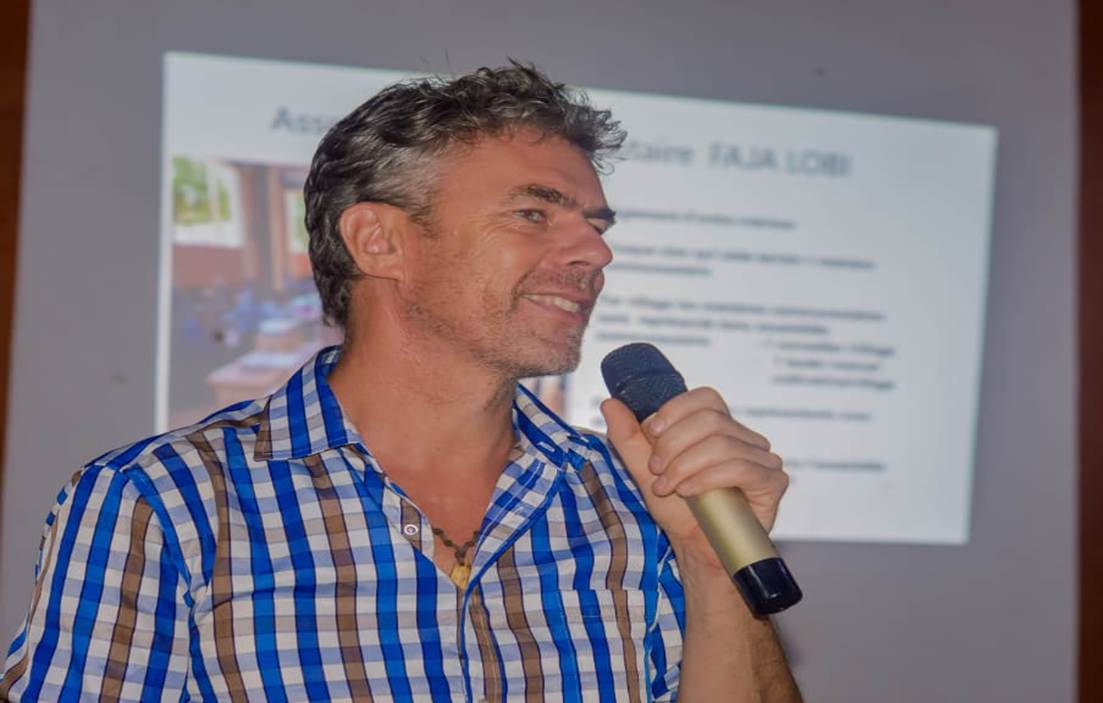 Jurgen Heytens parle au micro devant une projection intitulée Assemblée communautaire Faja Lobi.