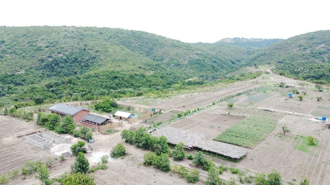 Vue aérienne d’une vallée verdoyante avec des bâtiments, des étangs et des parcelles cultivées.