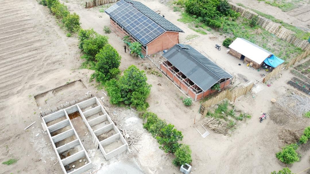Vue aérienne des bassins de l’écloserie à côté de deux bâtiments, dont un couvert de panneaux solaires.
