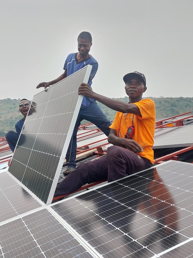 Deux techniciens installent un panneau solaire sur un toit.