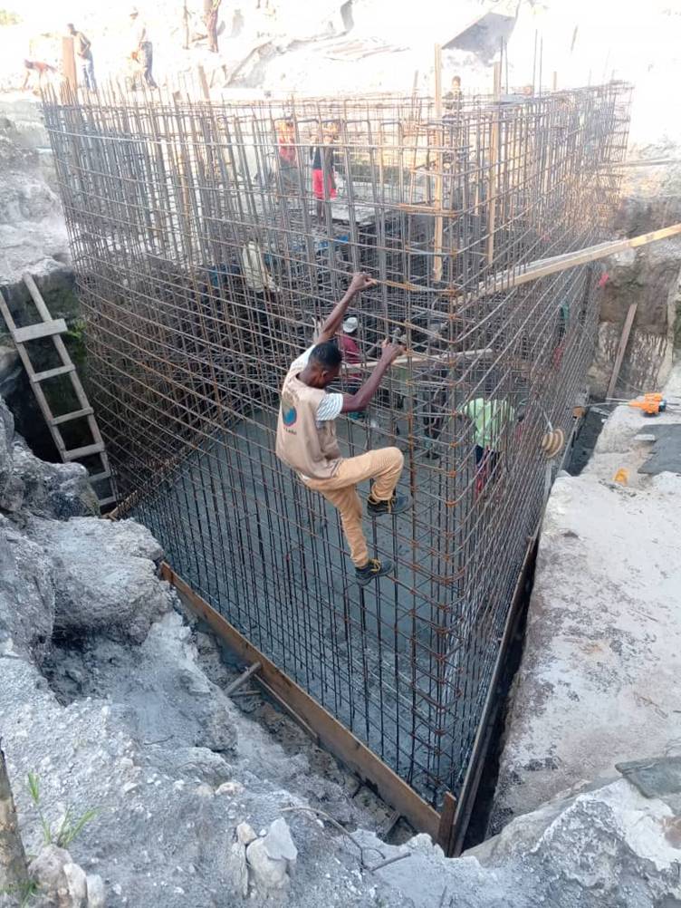 Un ouvrier grimpe le long d’une cage d’armatures métalliques dans une fosse.
