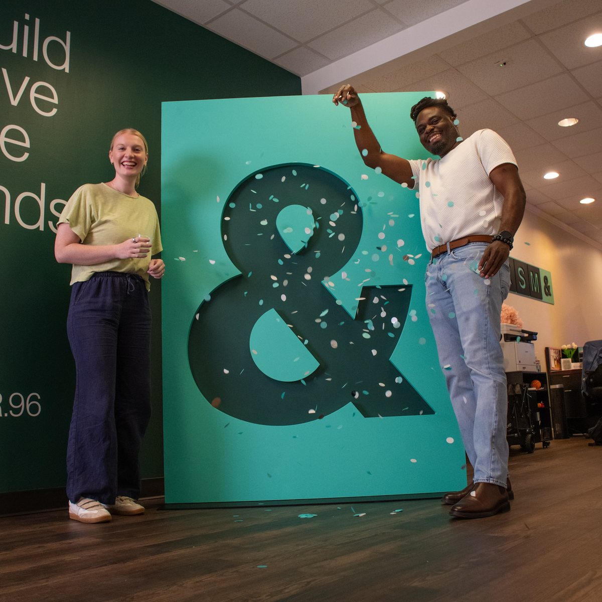 Two RSM& team members with a branded ampersand build