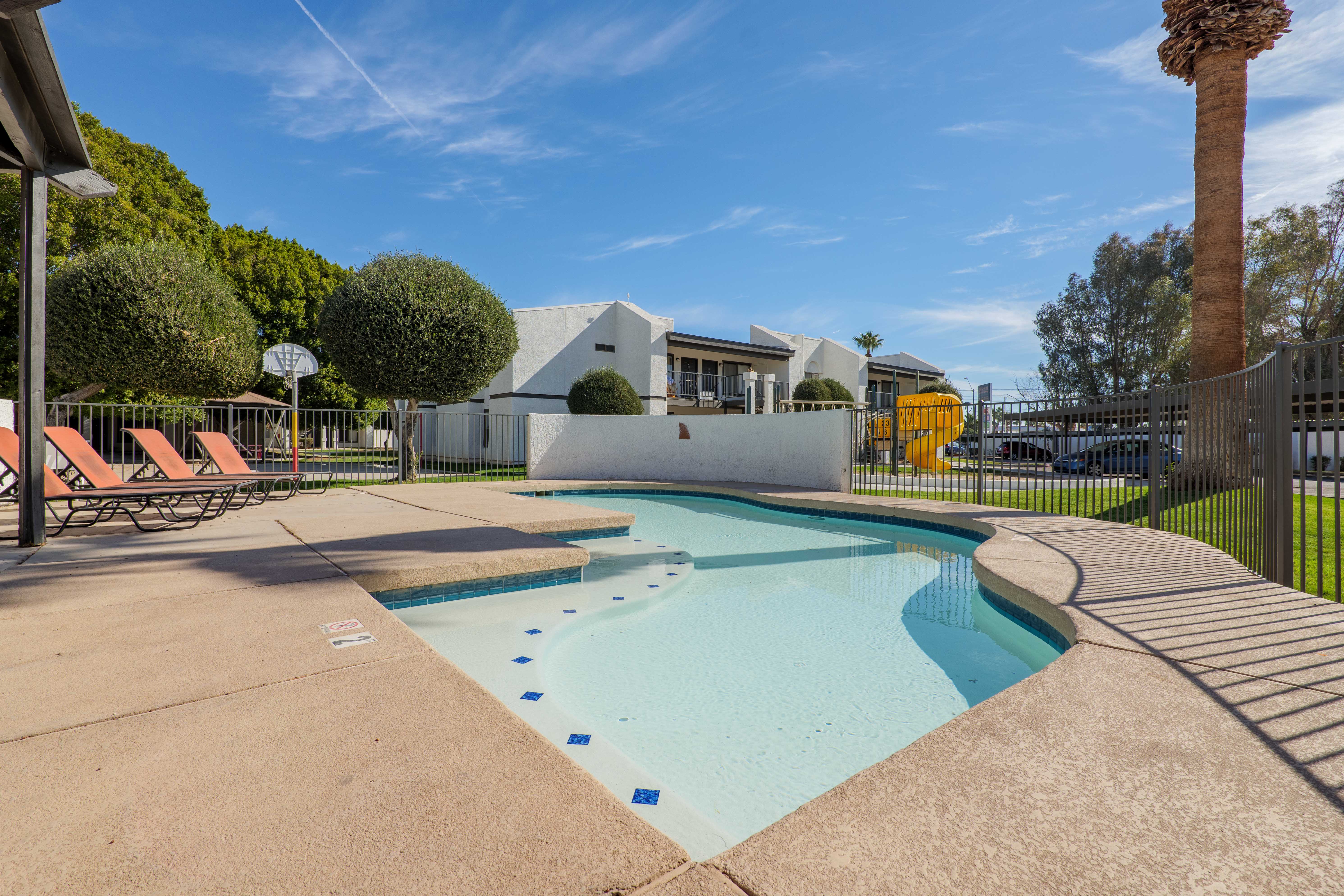 Swimming pool with red lounge chairs overlooking playground