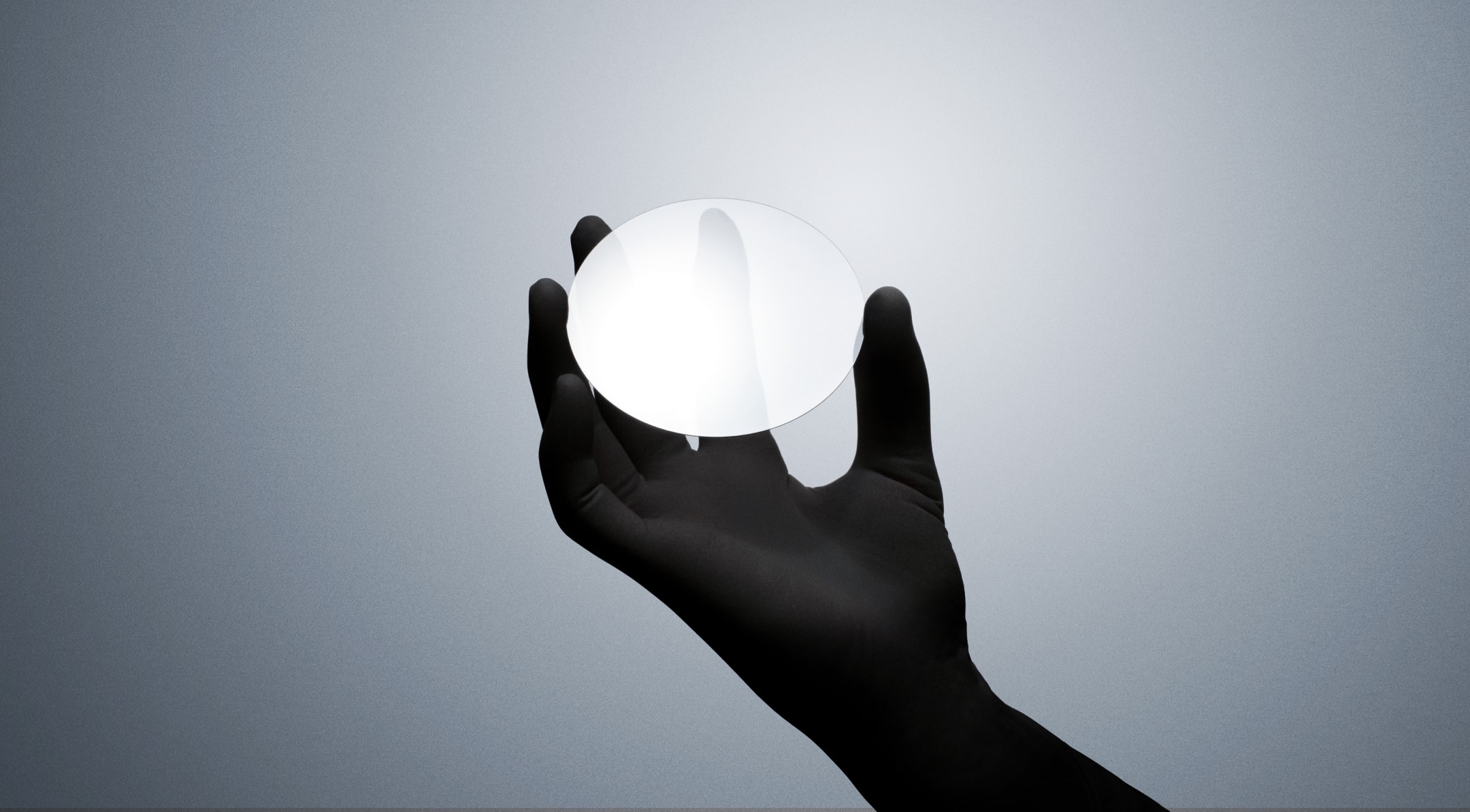 A hand holding a single crystal diamond wafer.