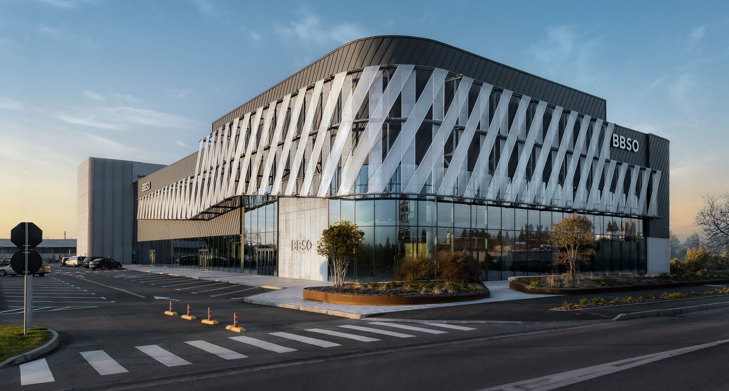 Campus BBSO at sunset, with perforated metal ribbons wrapping the curved glazed facade