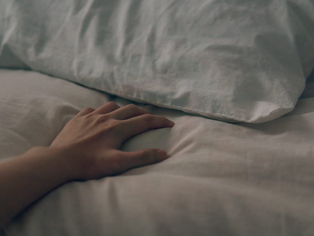 Main lissant une housse de couette blanche sur un lit