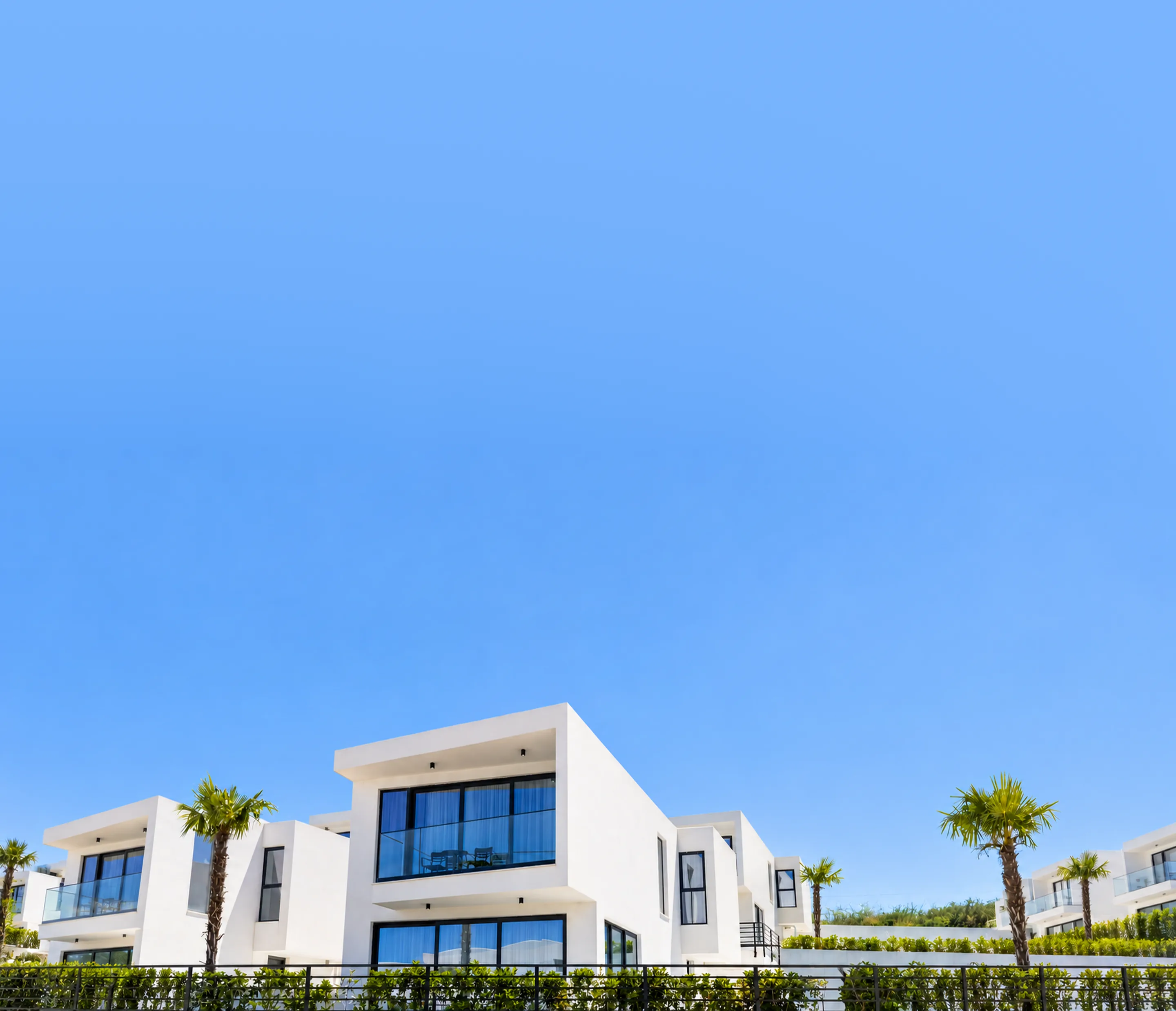 Maisons contemporaines blanches aux menuiseries noires, sous un ciel bleu