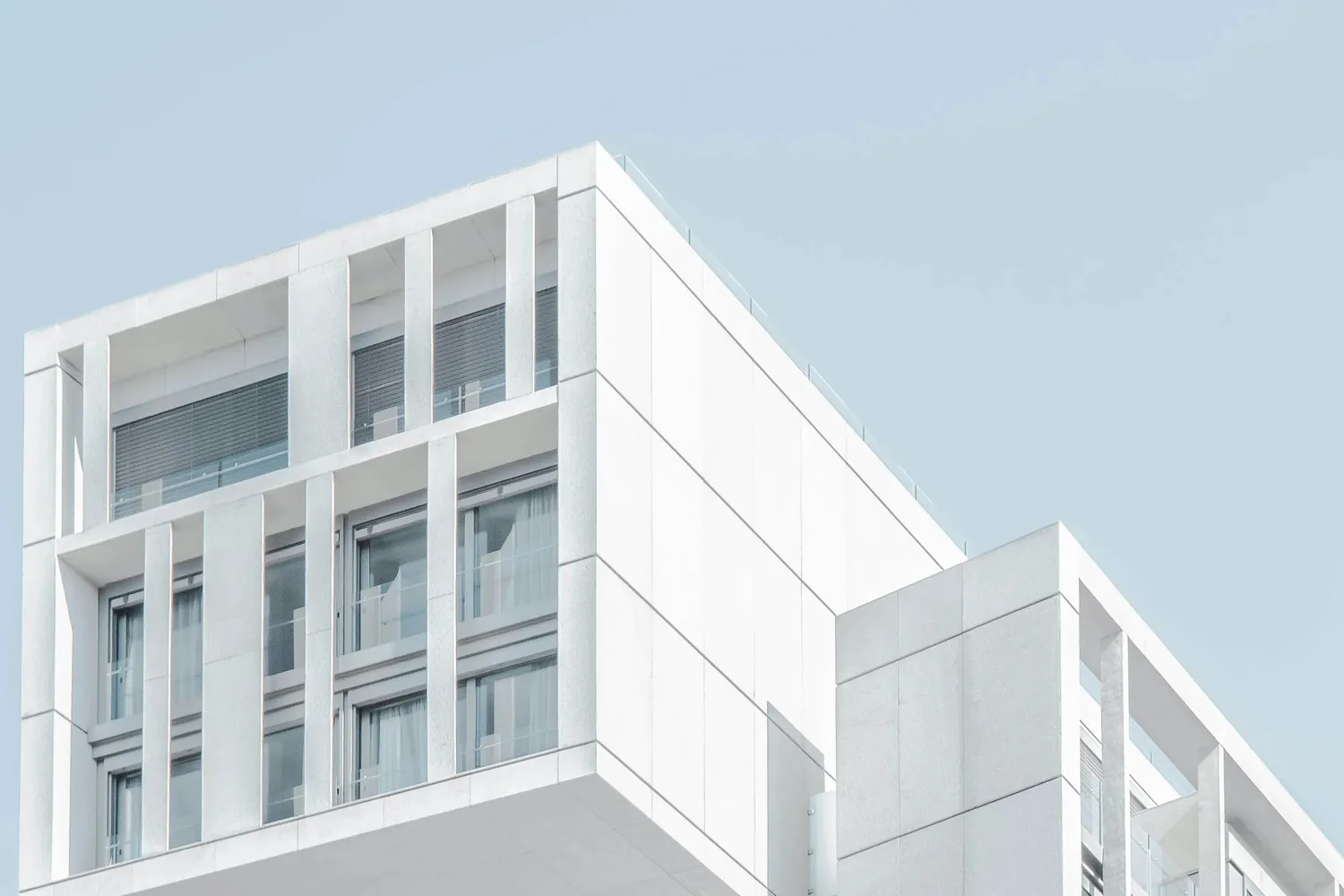 Immeuble résidentiel moderne aux façades blanches, sous un ciel bleu clair