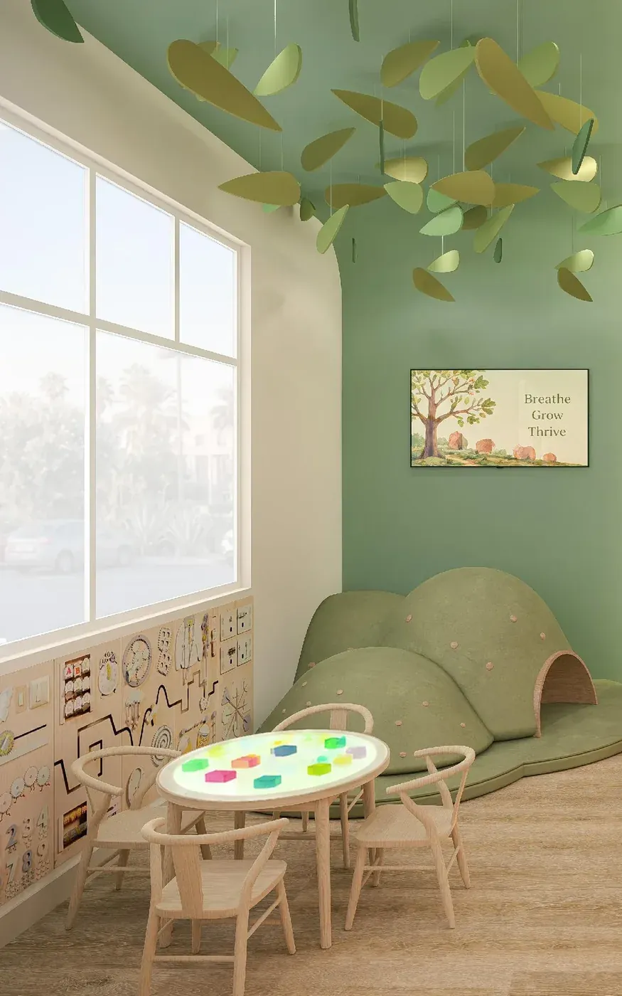 Kids' play corner with a small table, climbing hills and a Breathe Grow Thrive sign